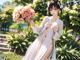 A woman in a white kimono holding a bouquet of flowers.