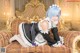 A woman in a maid outfit sitting on a couch.