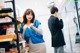 A woman standing in front of a refrigerator in a store.