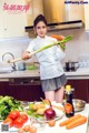 A woman holding a bunch of vegetables in a kitchen.