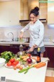 A woman in a kitchen preparing food on a counter.