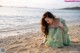 A woman in a green dress sitting on the beach.