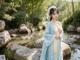 A woman in a blue dress standing next to a pond.