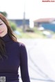 A woman in a purple turtleneck sweater smiles at the camera.