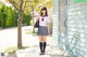 A woman in a school uniform standing in front of a house.