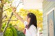 A woman in a school uniform reaching up to touch a tree.