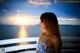 A woman standing on a balcony looking out at the ocean.