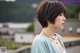 A woman with a short brown hair wearing a necklace.