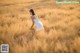 A woman in a white dress standing in a field of tall grass.